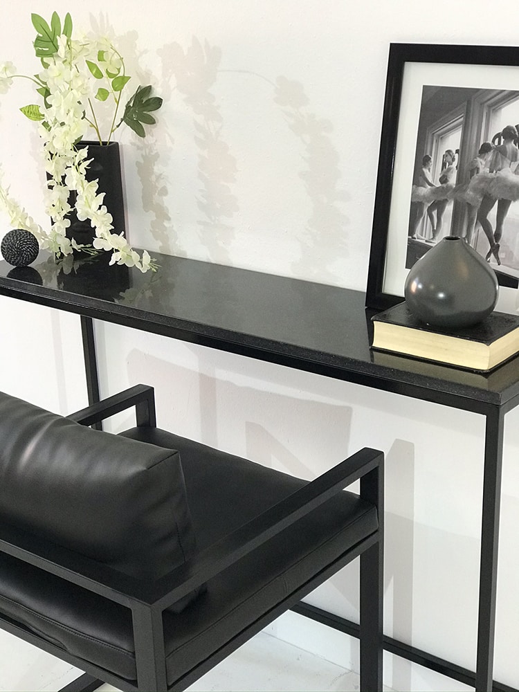 console design avec plateau en marbre granit noir et pied minimaliste en acier laqué noir