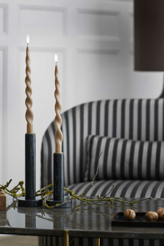 canapé Lounge en tissu à rayures, associé à une table basse en marbre sur laquelle sont positionnées 2 élégantes bougies.
