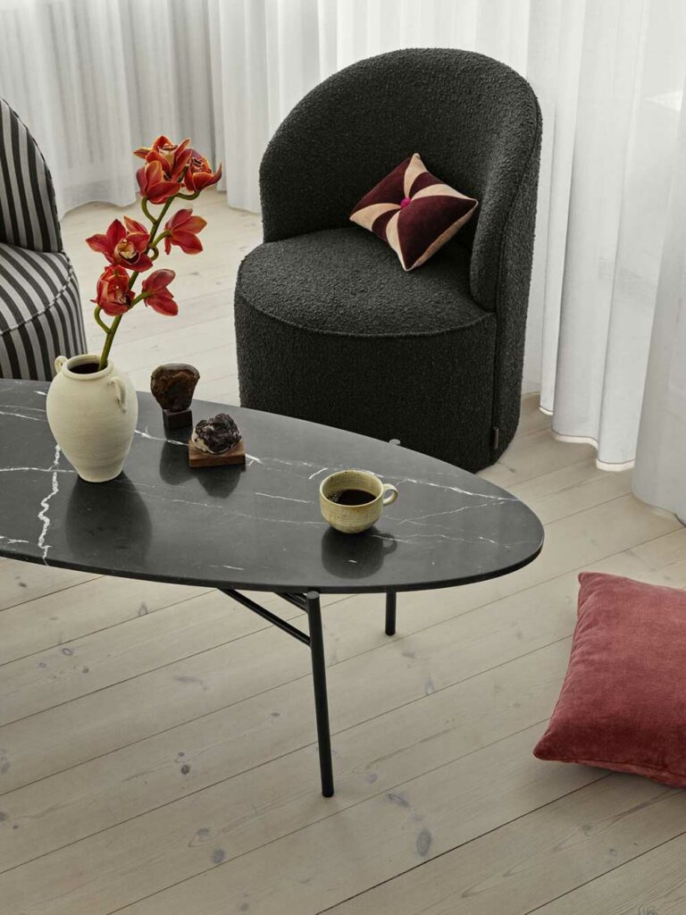 fauteuil Lounge en tissu doux bouclé gris charbon et une table basse ovale en marbre noir.