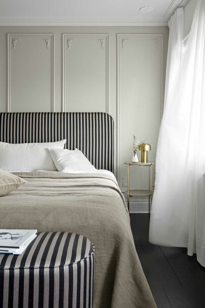 Table de chevet à côté de son lit matrimonial avec dominante de couleurs grises.