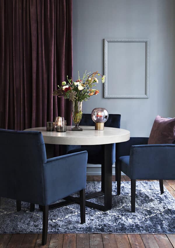 Table à manger ronde et chaises élégantes avec accoudoirs, en velours bleu.
